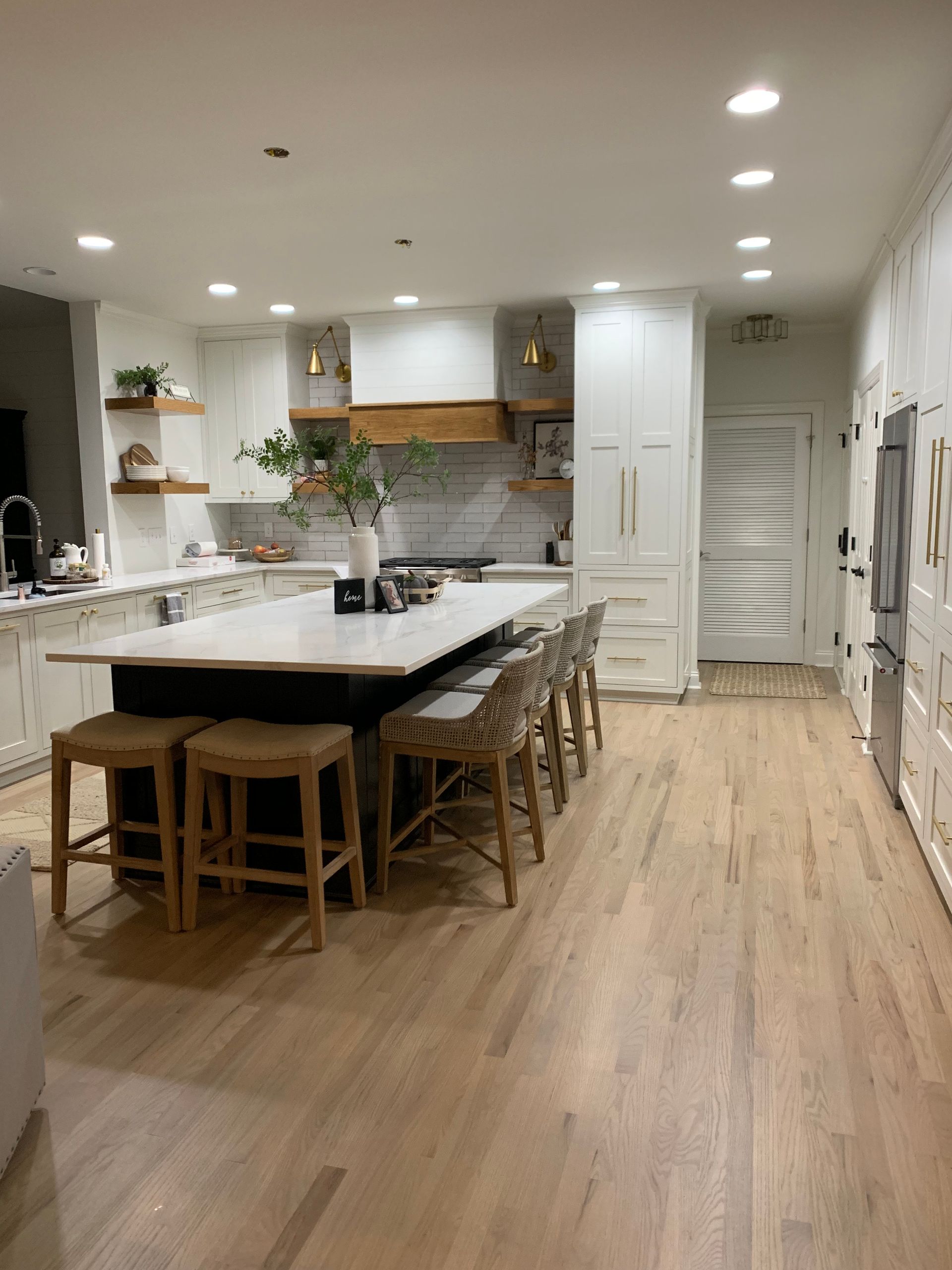 A kitchen with a large island and stools in it.