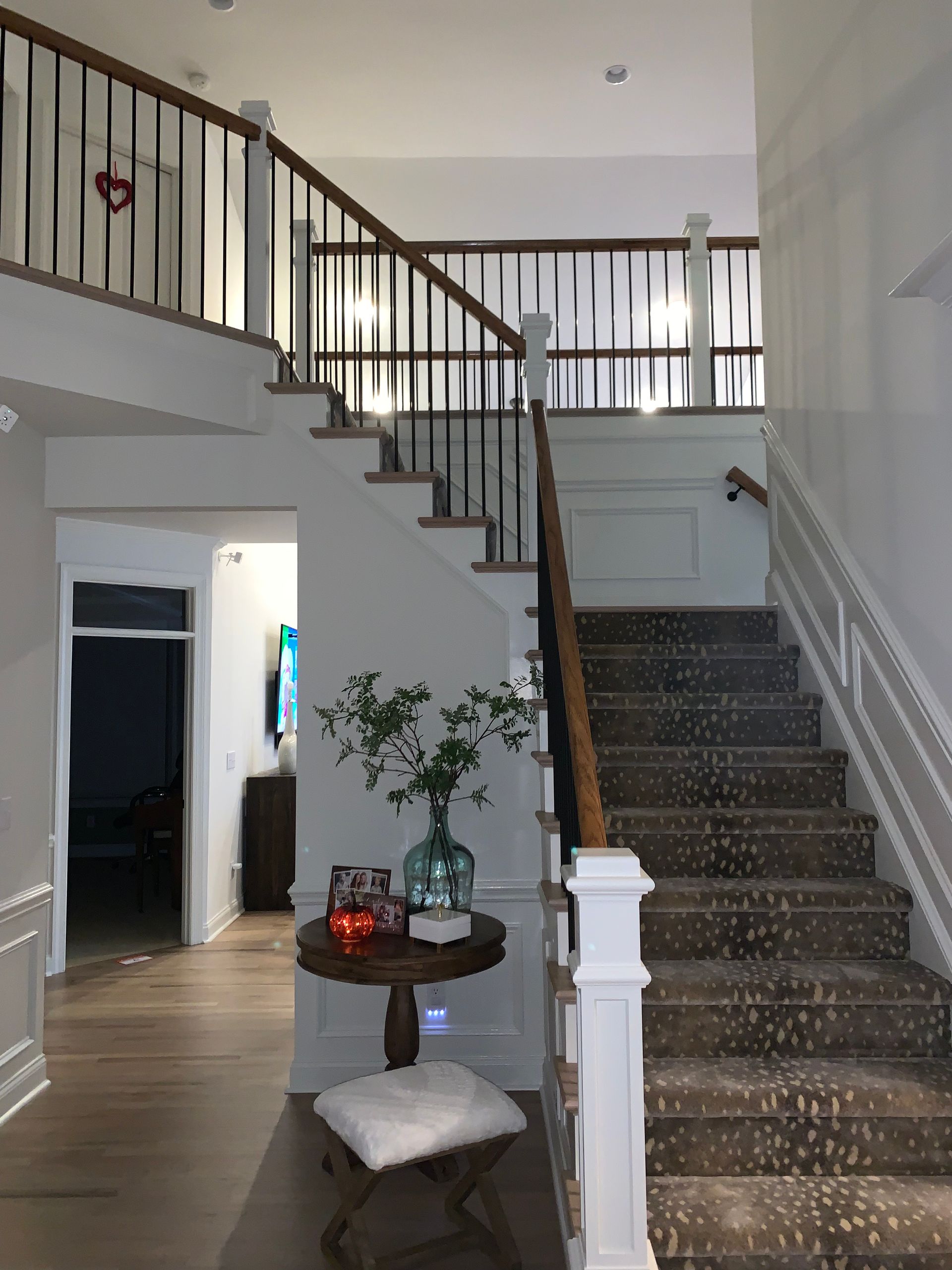 A hallway with stairs and a table in the middle of it.