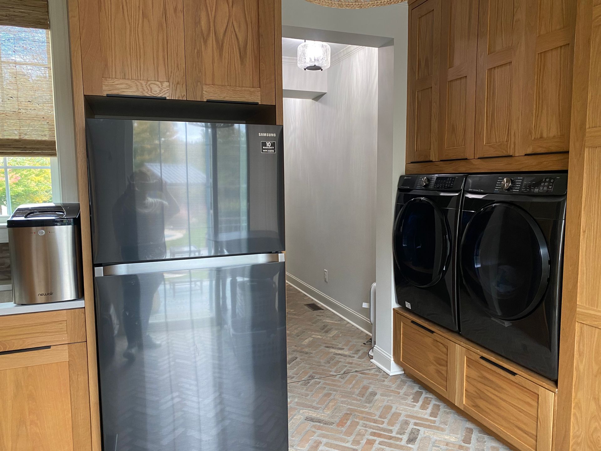 A kitchen with a refrigerator , washer and dryer , and wooden cabinets.