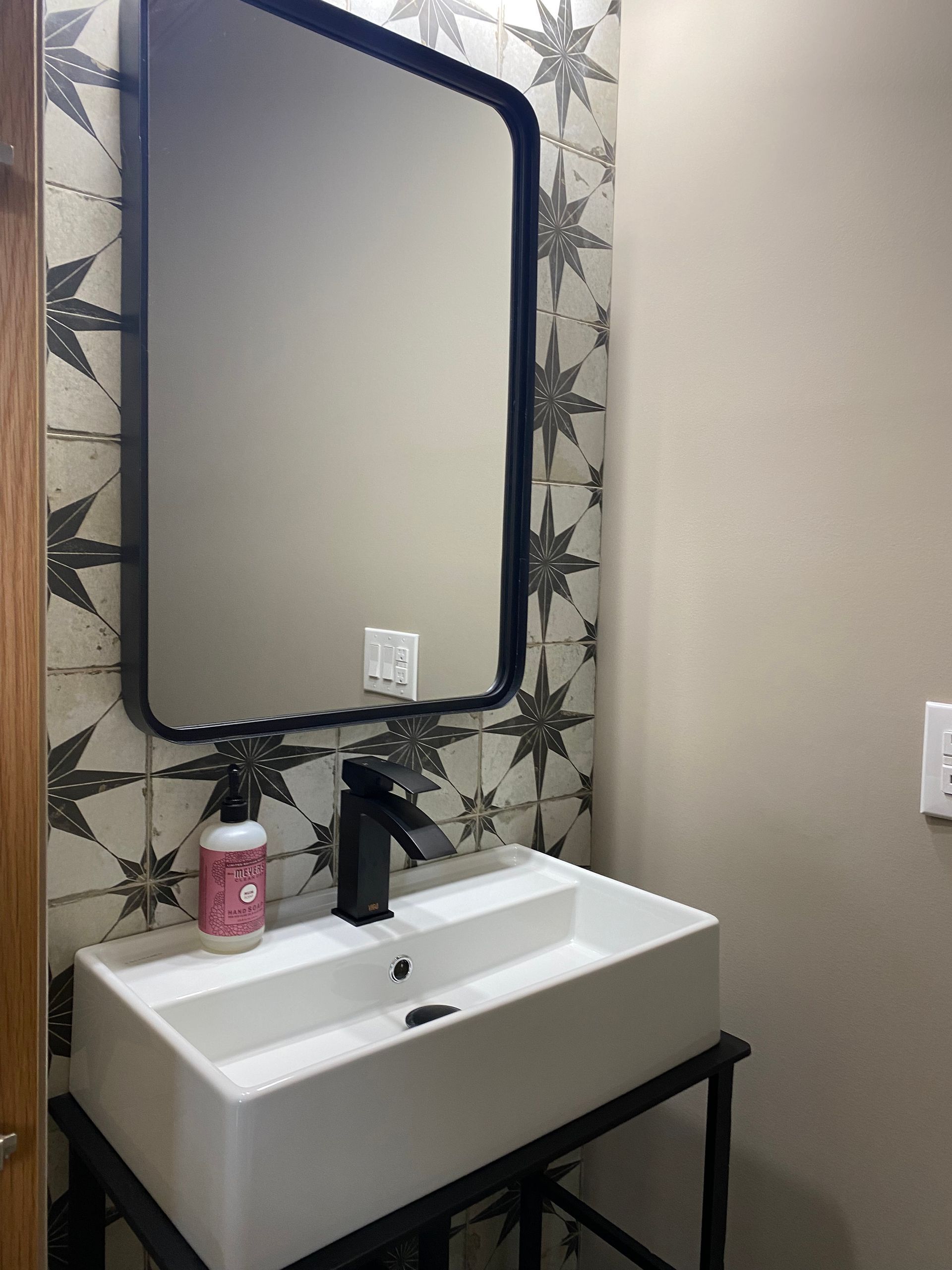 A bathroom with a sink , mirror and soap dispenser.