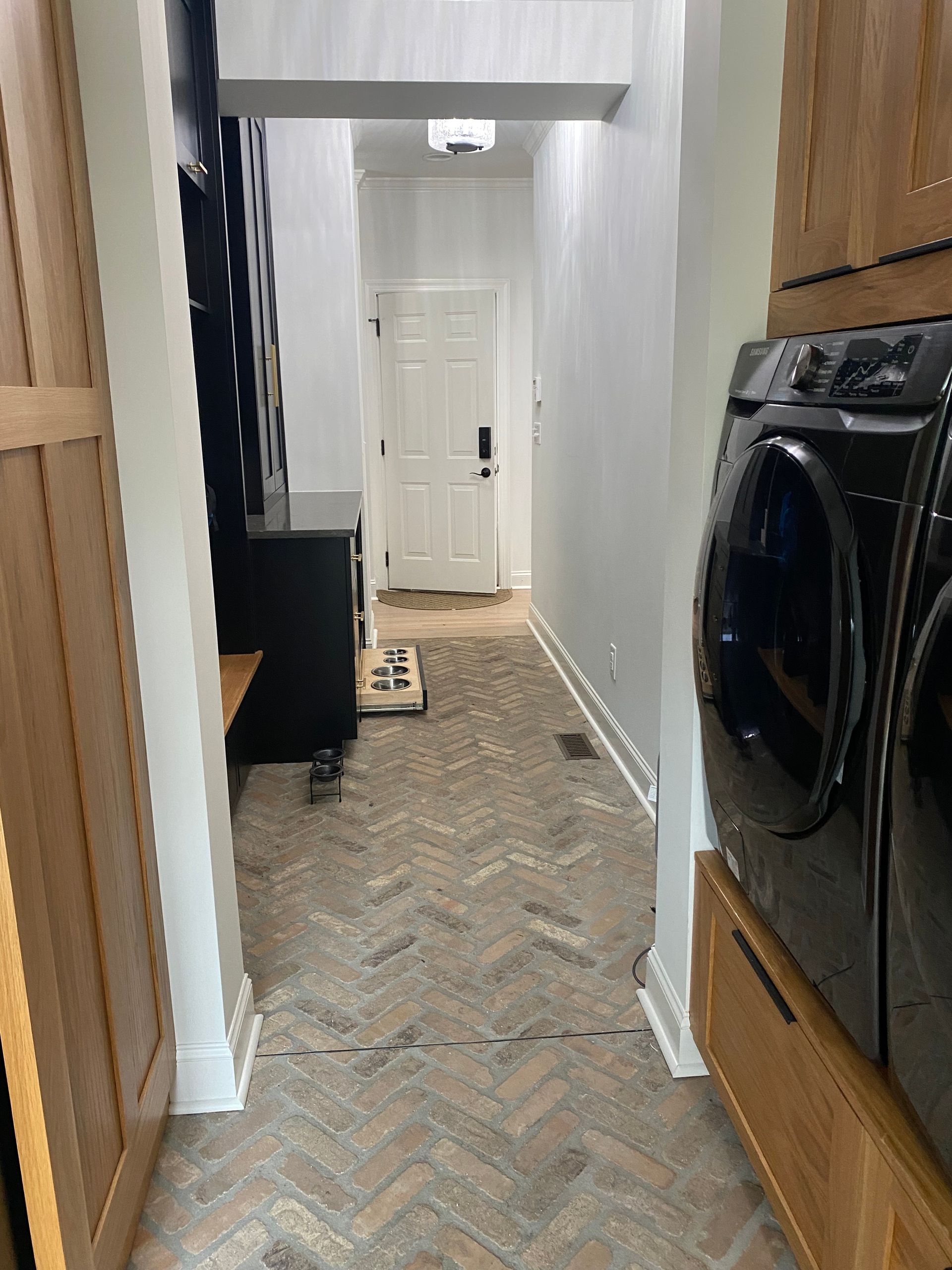 A laundry room with a washer and dryer and a herringbone floor.