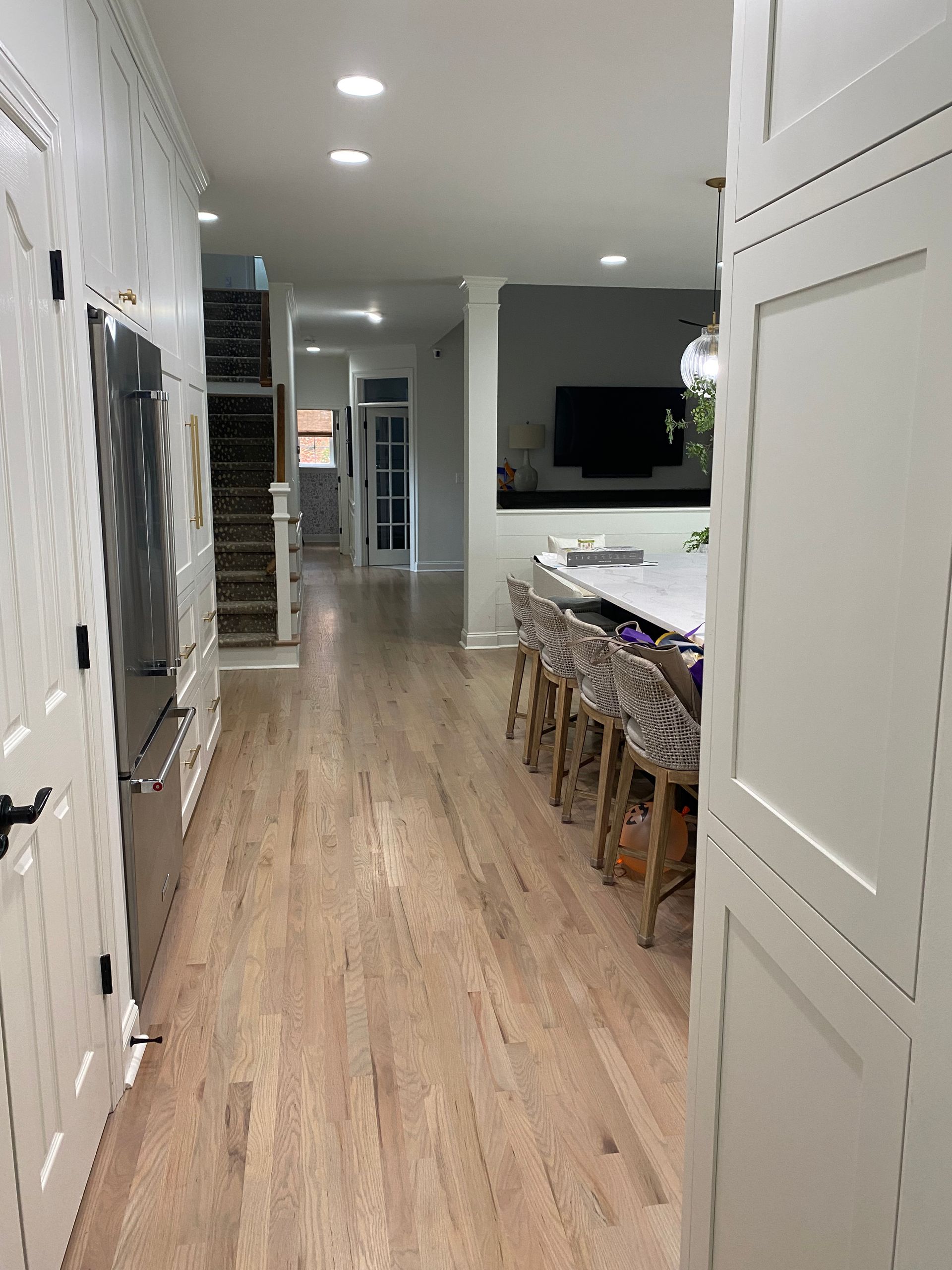 A long hallway in a house with hardwood floors and a table and chairs.