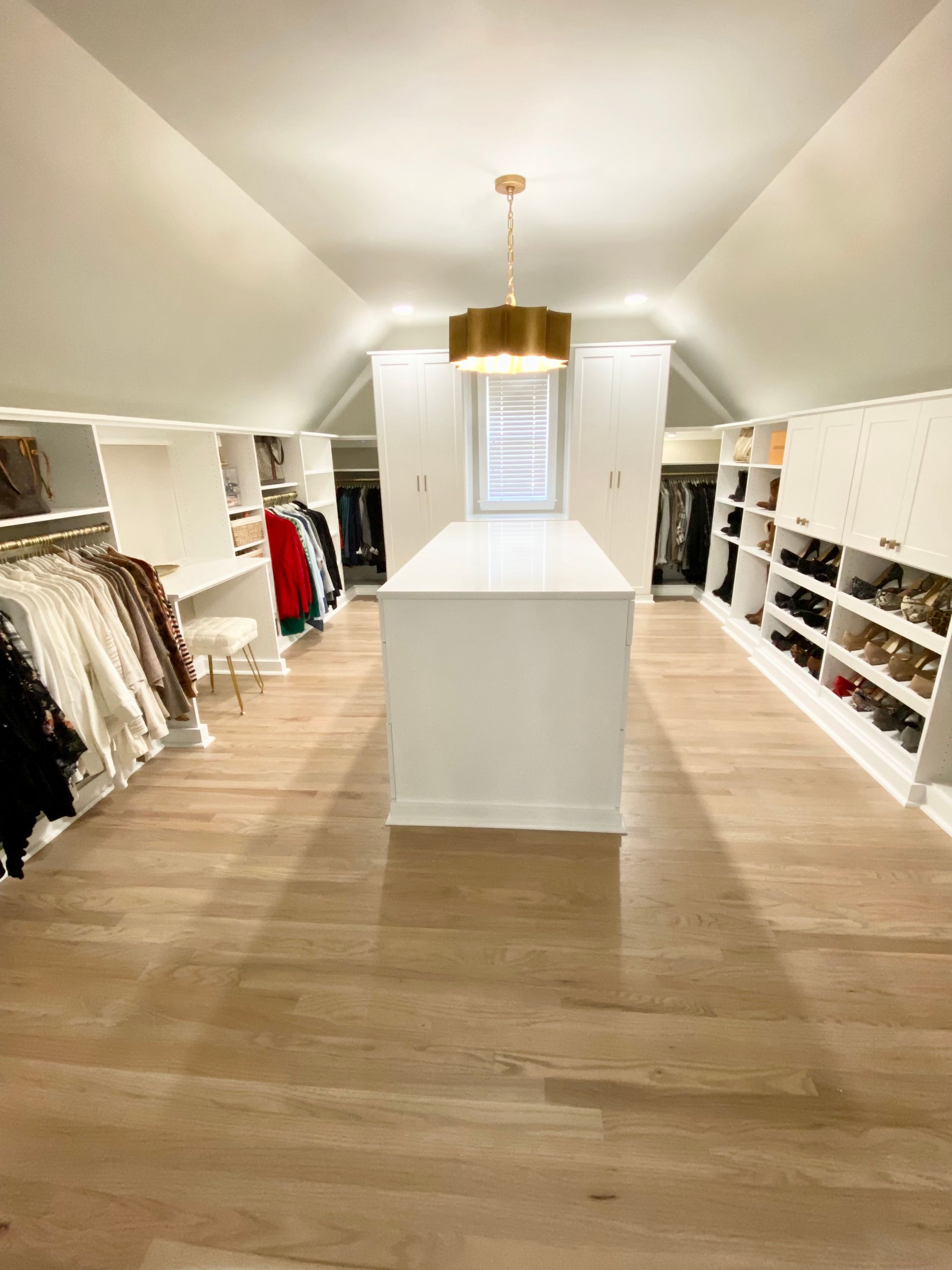 A large walk in closet with a large island in the middle.