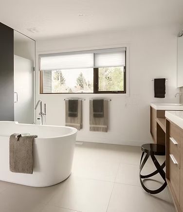 A bathroom with a tub, sink, and window.