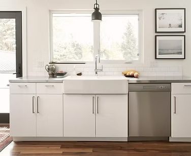 A kitchen with white cabinets, a sink, a dishwasher, and a window.