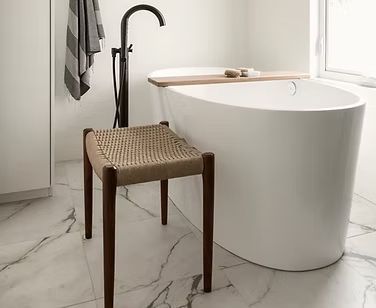 A stool is sitting next to a bathtub in a bathroom.