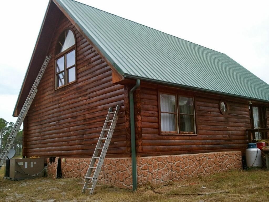 A log cabin with a green roof and a ladder