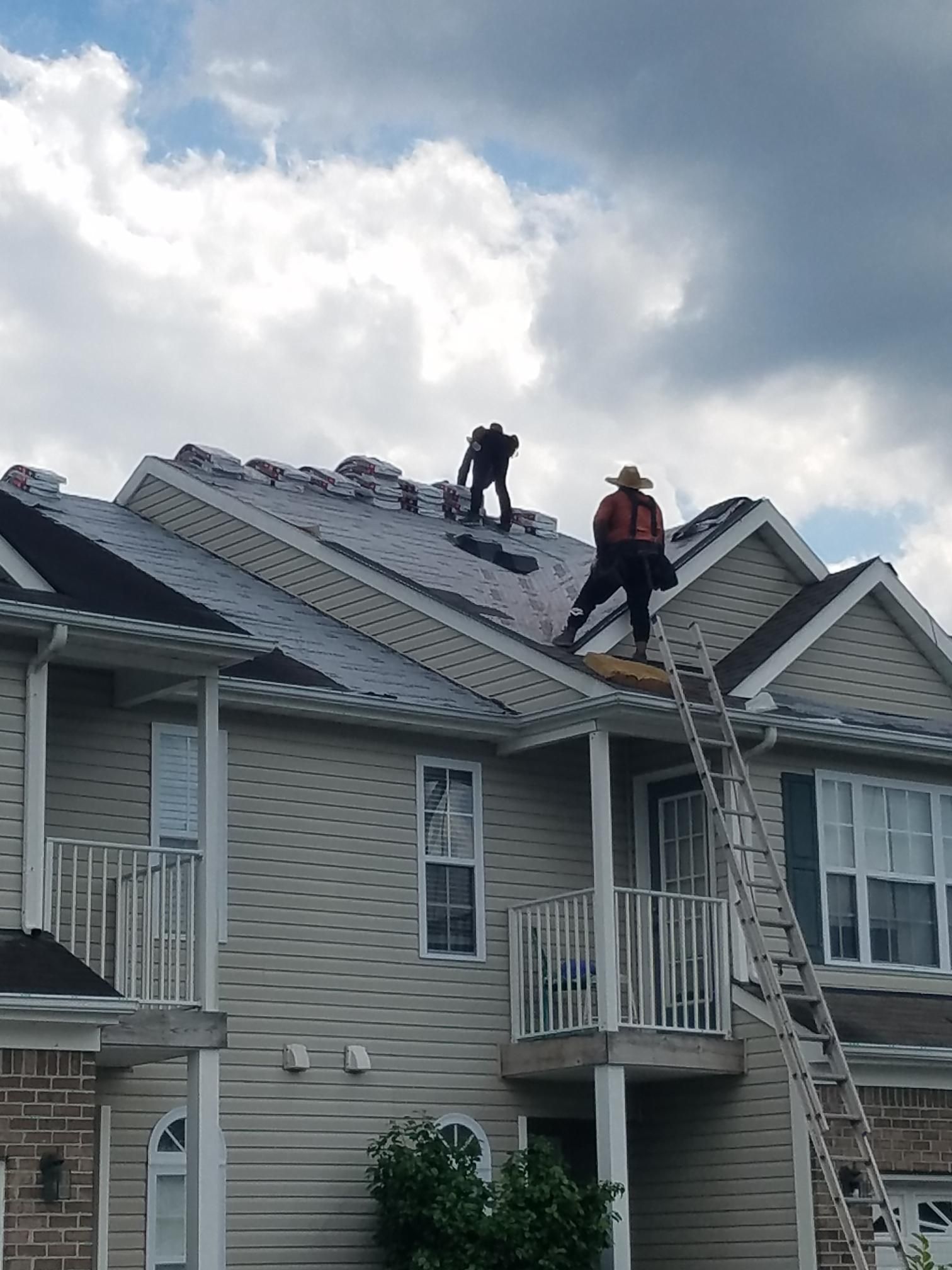 Two men are working on the roof of a house