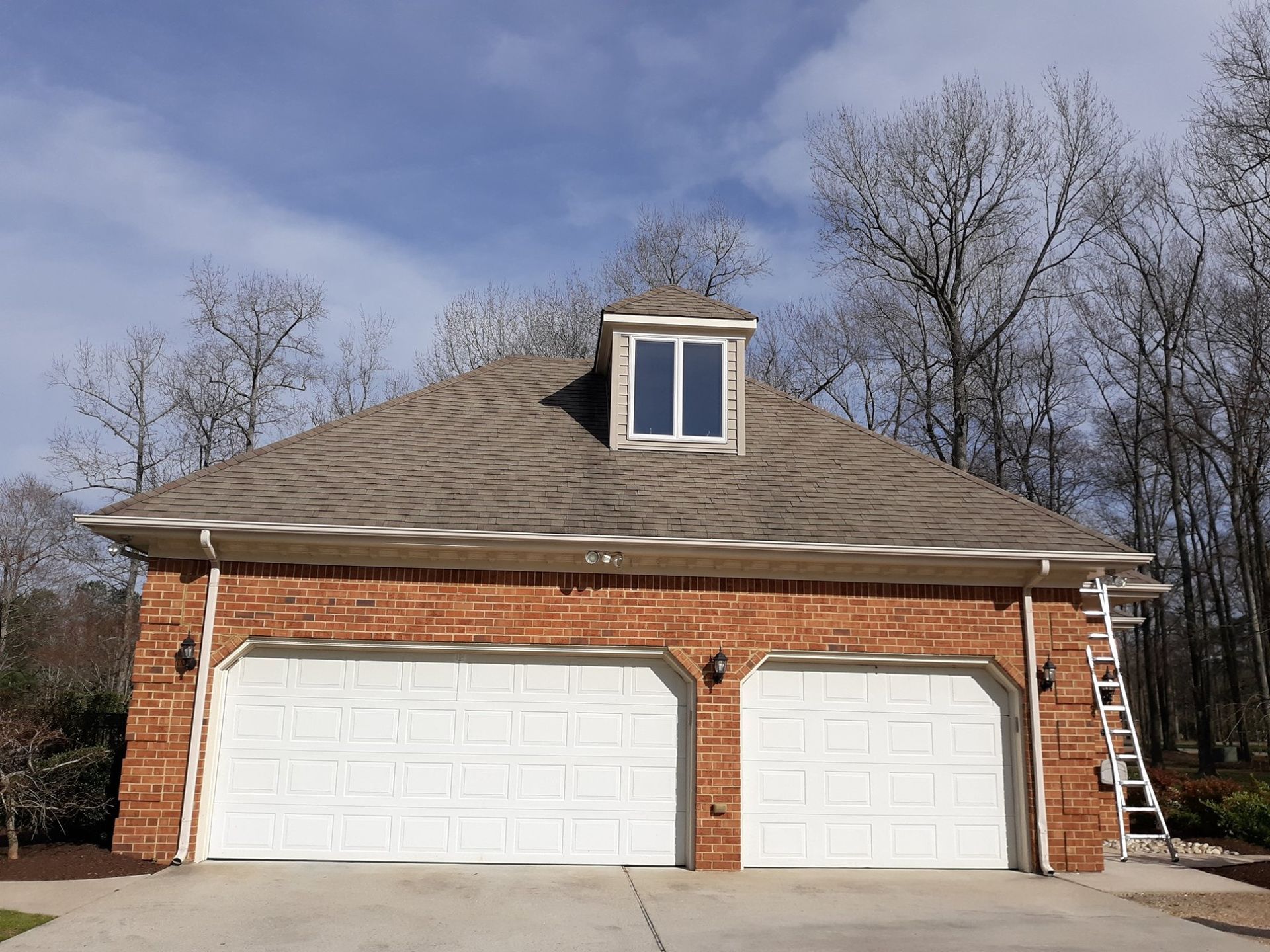 A brick garage with two white garage doors and a window
