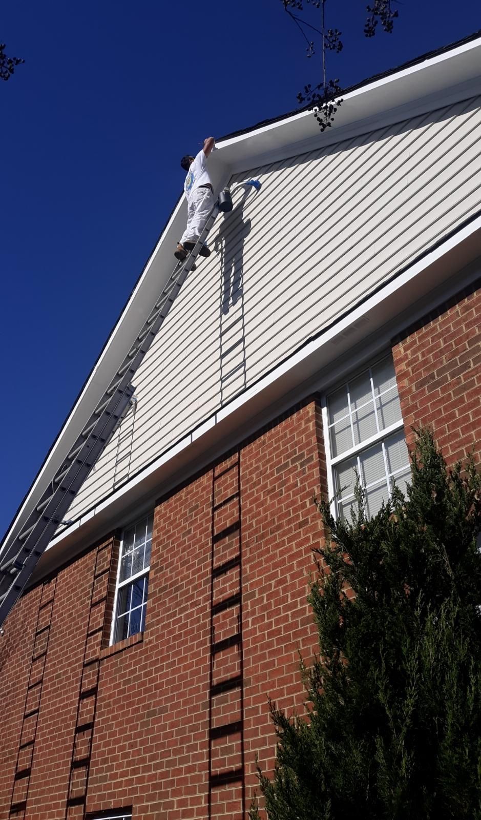 A man is painting the side of a brick building with a ladder