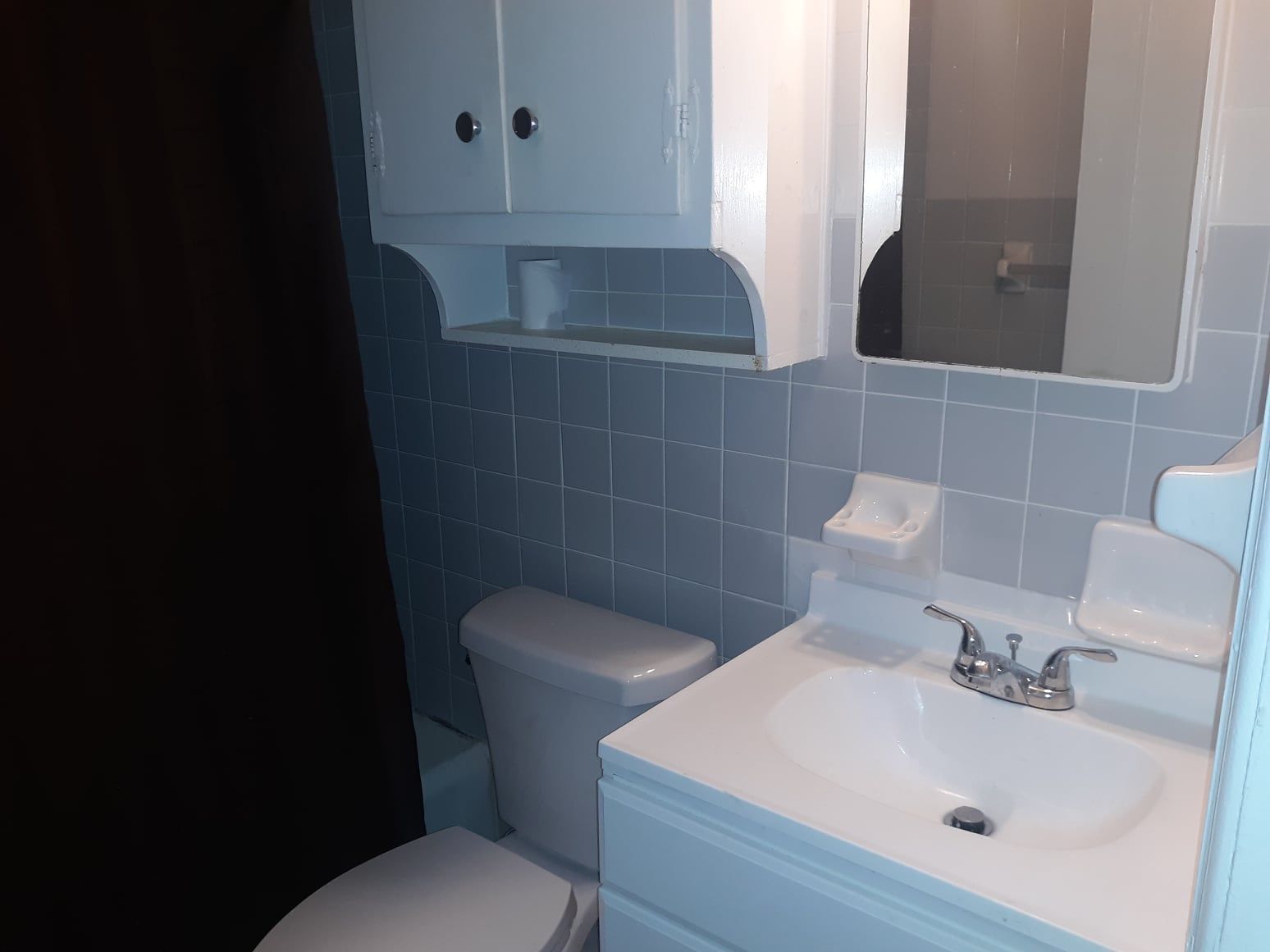 A bathroom with a toilet, sink and mirror