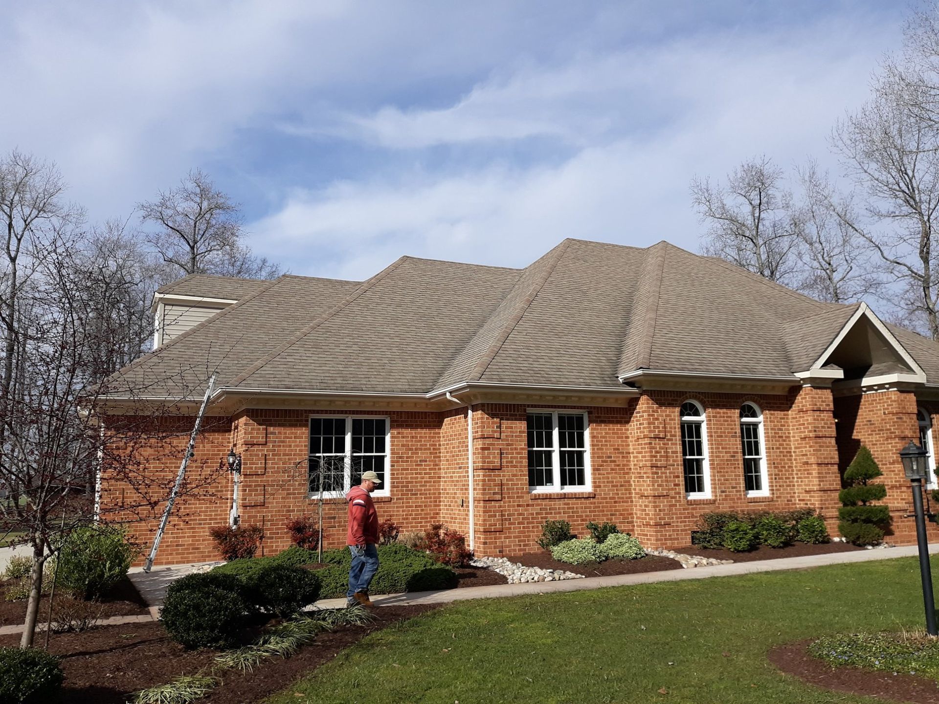 A man is standing in front of a large brick house