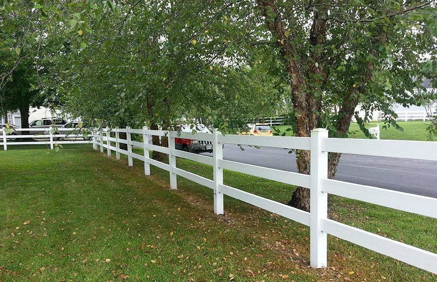 A white fence surrounds a lush green field.