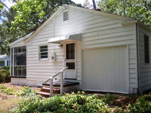 A small white house with a garage and stairs