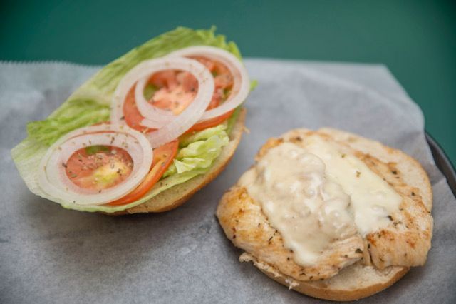 Chicken sandwich open, with lettuce, tomato, onion.