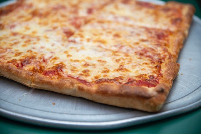 Square cheese pizza on a metal tray.