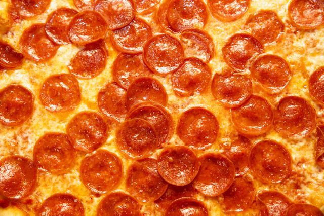 Pepperoni pizza, overhead shot, close-up of many circular pepperoni slices on a cheesy crust.
