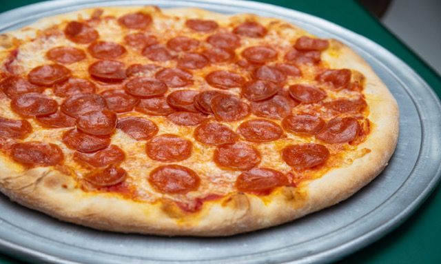 Pepperoni pizza on a metal tray, with a golden-brown crust.