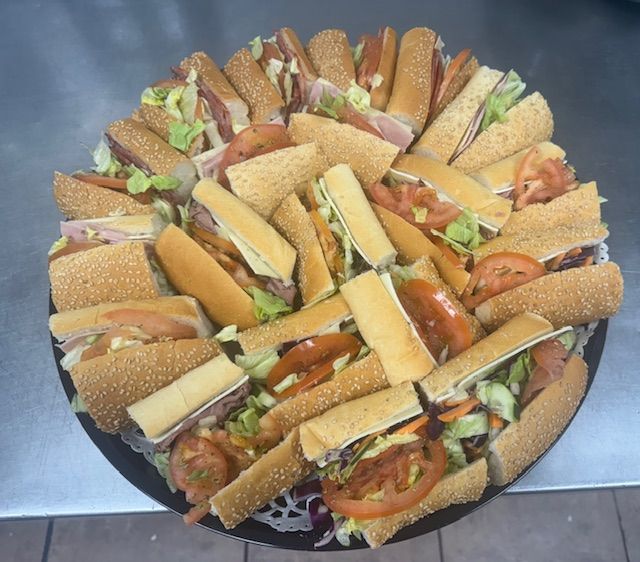 Sandwich platter with various fillings, including lettuce, tomato, and meat, arranged on a black tray.