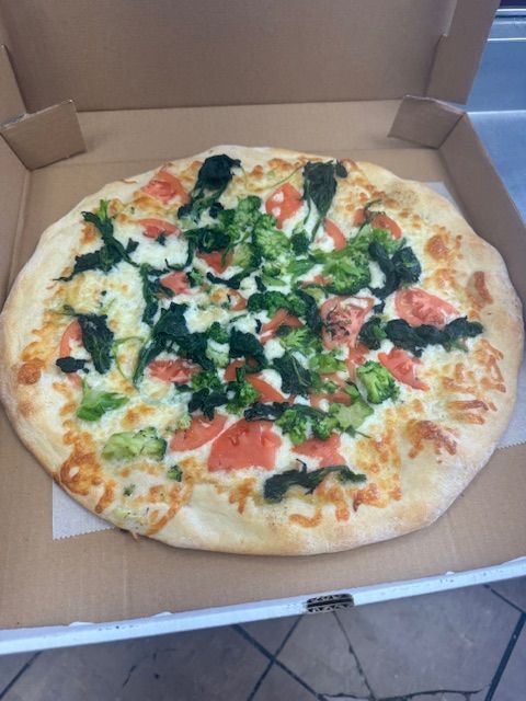 Pizza with broccoli, tomatoes, and cheese in an open cardboard box.
