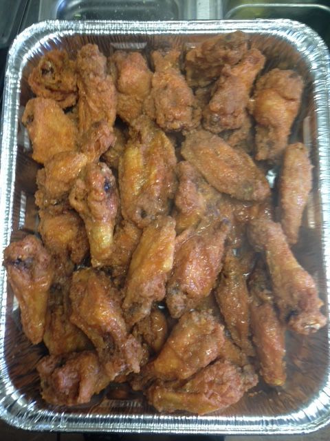 Tray of fried chicken wings in a foil container.