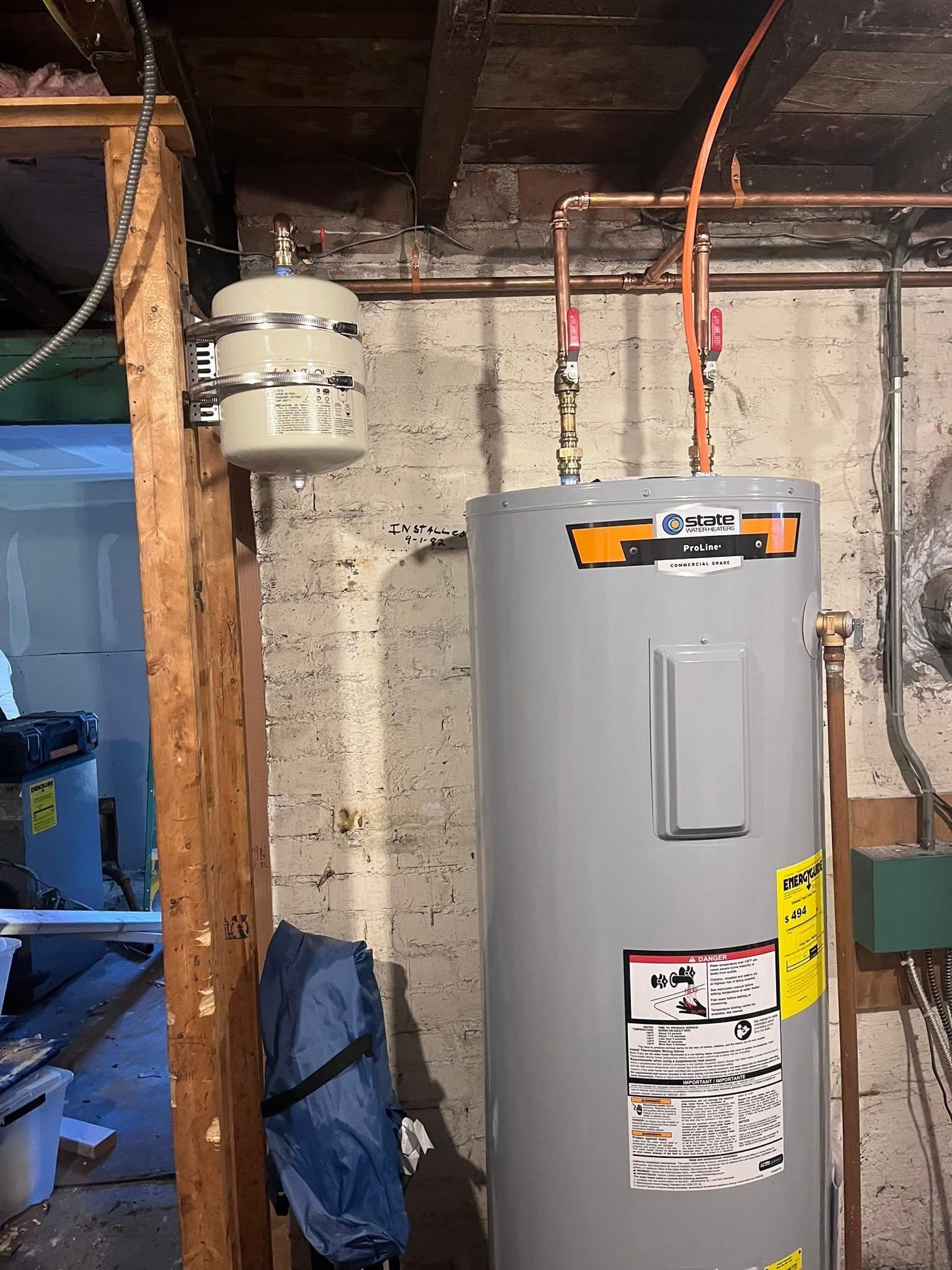 A residential water heater standing next to a wall-mounted thermal expansion tank in a basement.