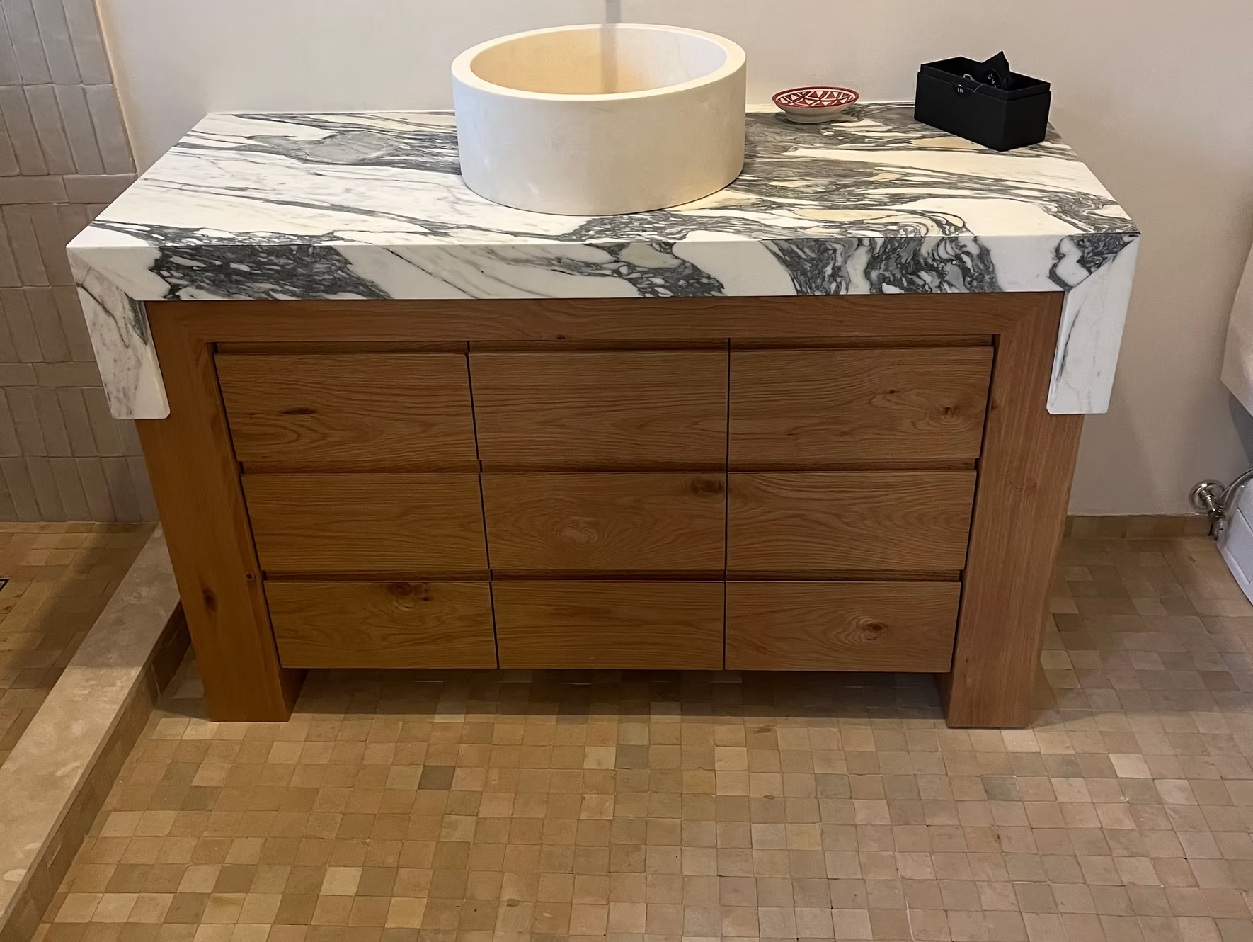 Wooden bathroom vanity with marble countertop and a white vessel sink.