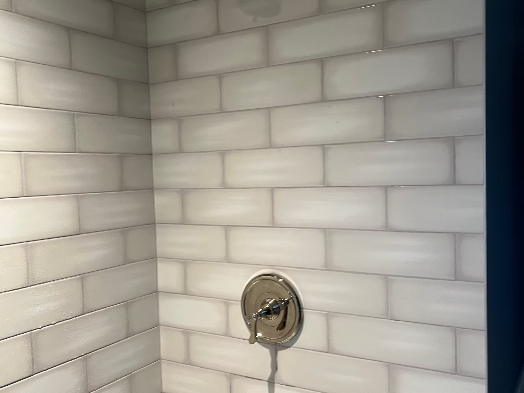 White tiled shower with silver faucet.