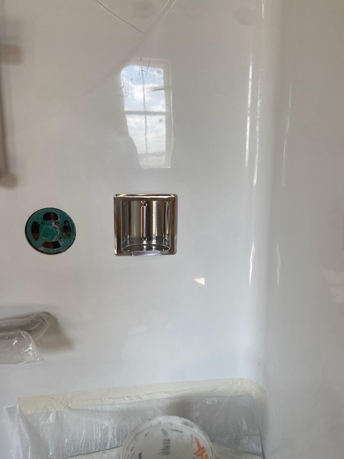 White shower interior with a faucet fixture and a light blue circle on the wall.