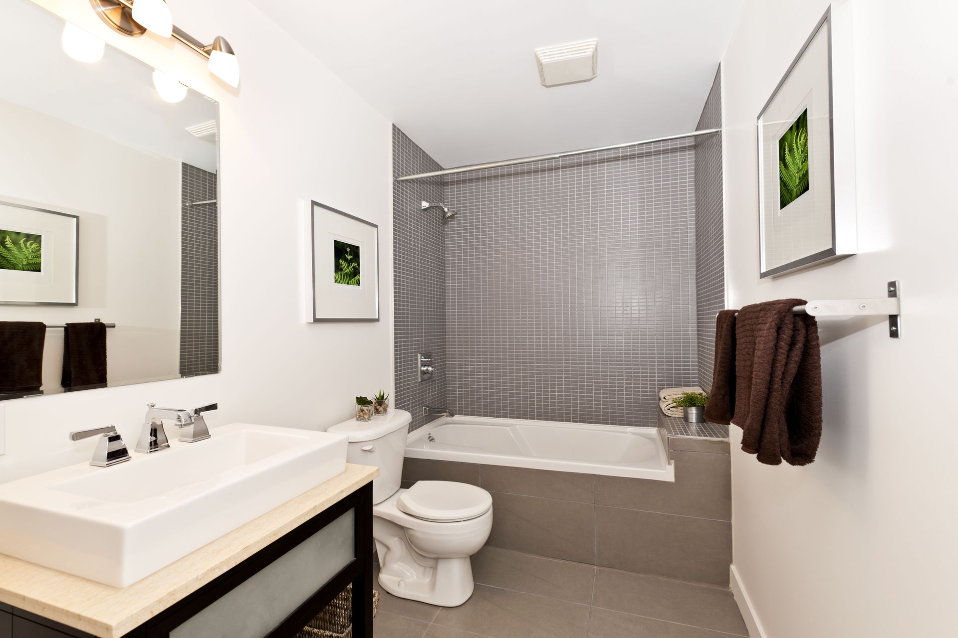 A white bathtub built into a beige tiled wall. The shower head hangs above.