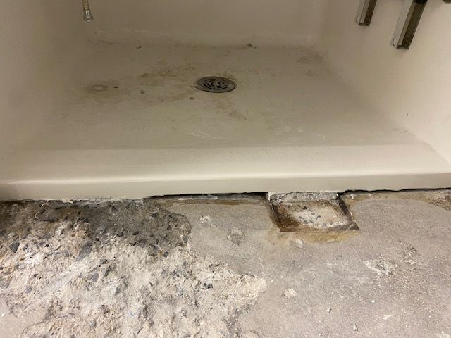 White shower wall with a vertical crack, near wooden framing - after