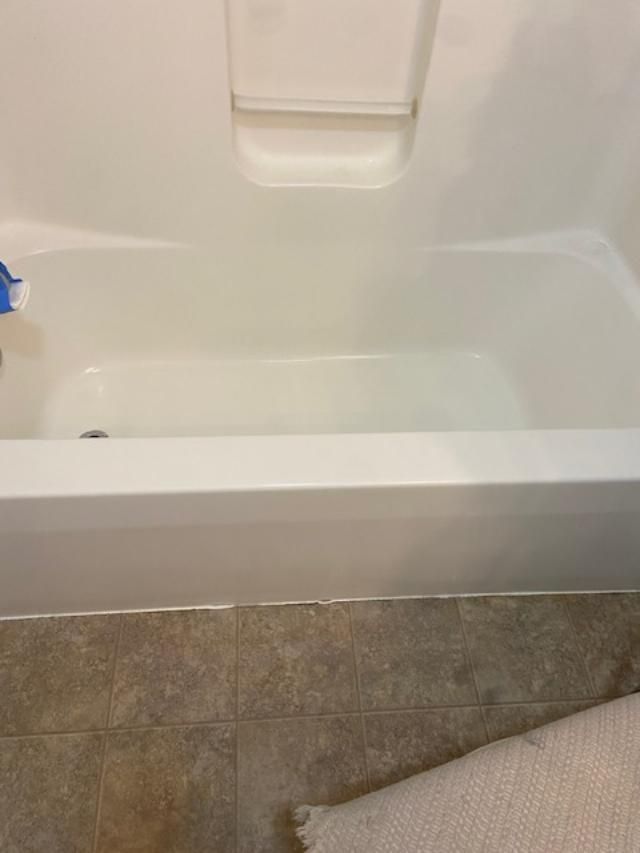 Bathtub with a built-in shower seat and gray tile floor, viewed from above