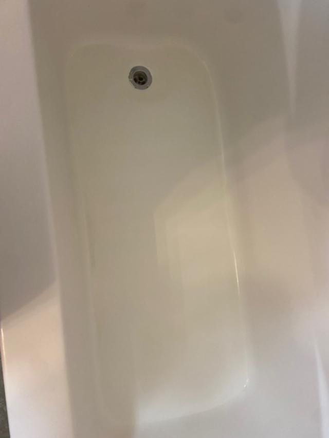 White bathtub interior with a drain near the top center.