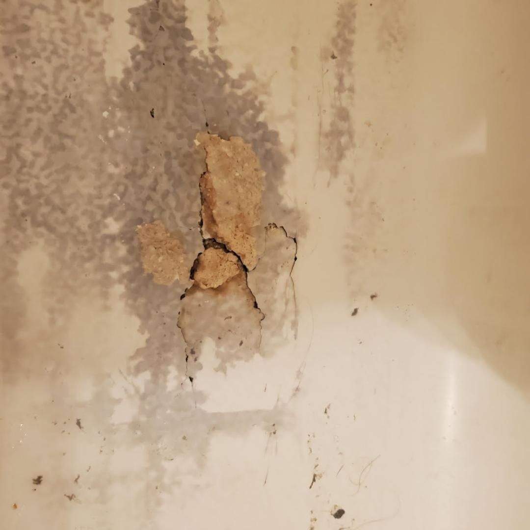 Peeling paint and water damage on a stained wall, with cracked plaster exposed.