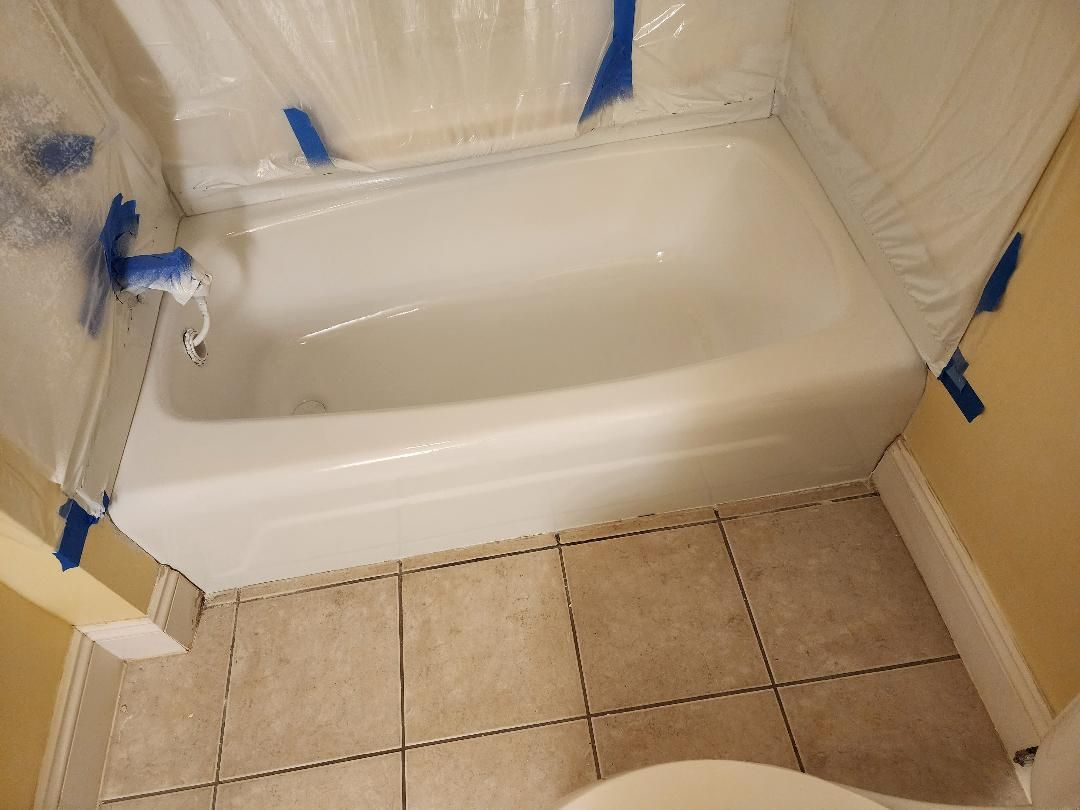 White bathtub inside a bathroom, covered in plastic sheeting for renovation. Beige floor tiles and yellow walls are visible.