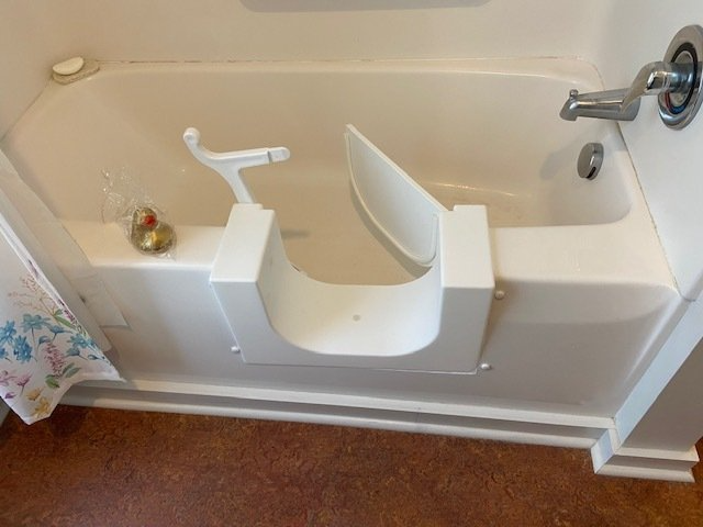 White walk-in bathtub with an open door and a seat for easy access in a bathroom.
