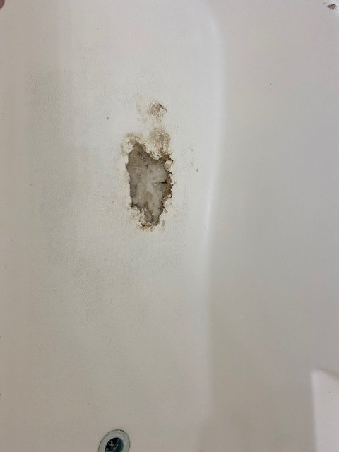 White bathtub with a damaged area, revealing the surface underneath the coating.