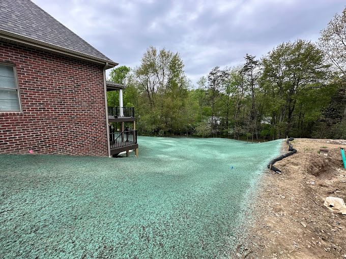A brick house with a green driveway in front of it.