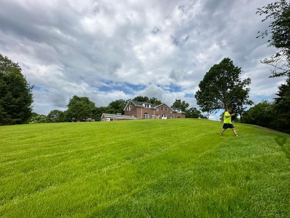 A person standing in a grassy field with a house in the background