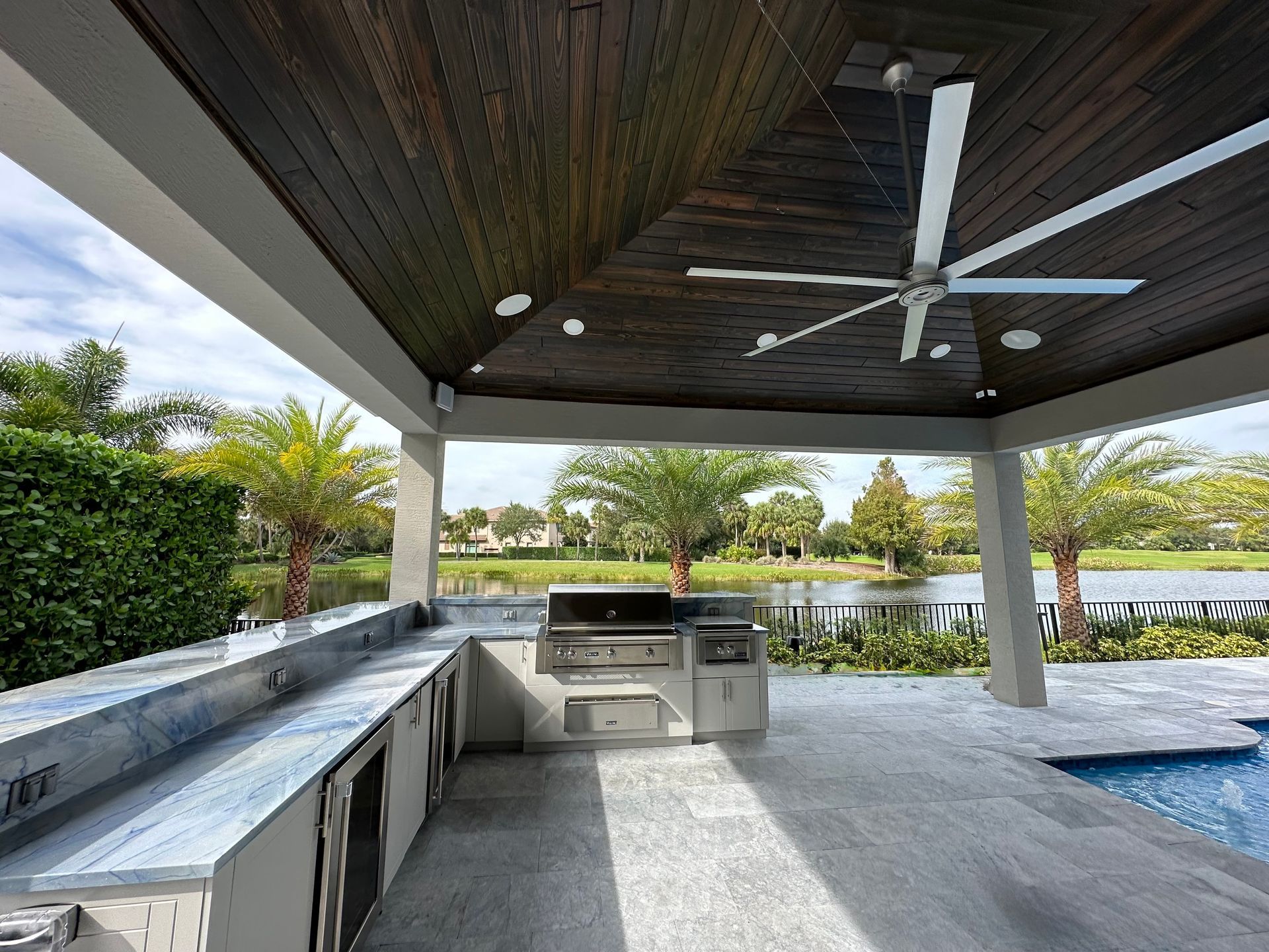 A large outdoor kitchen with a ceiling fan above it
