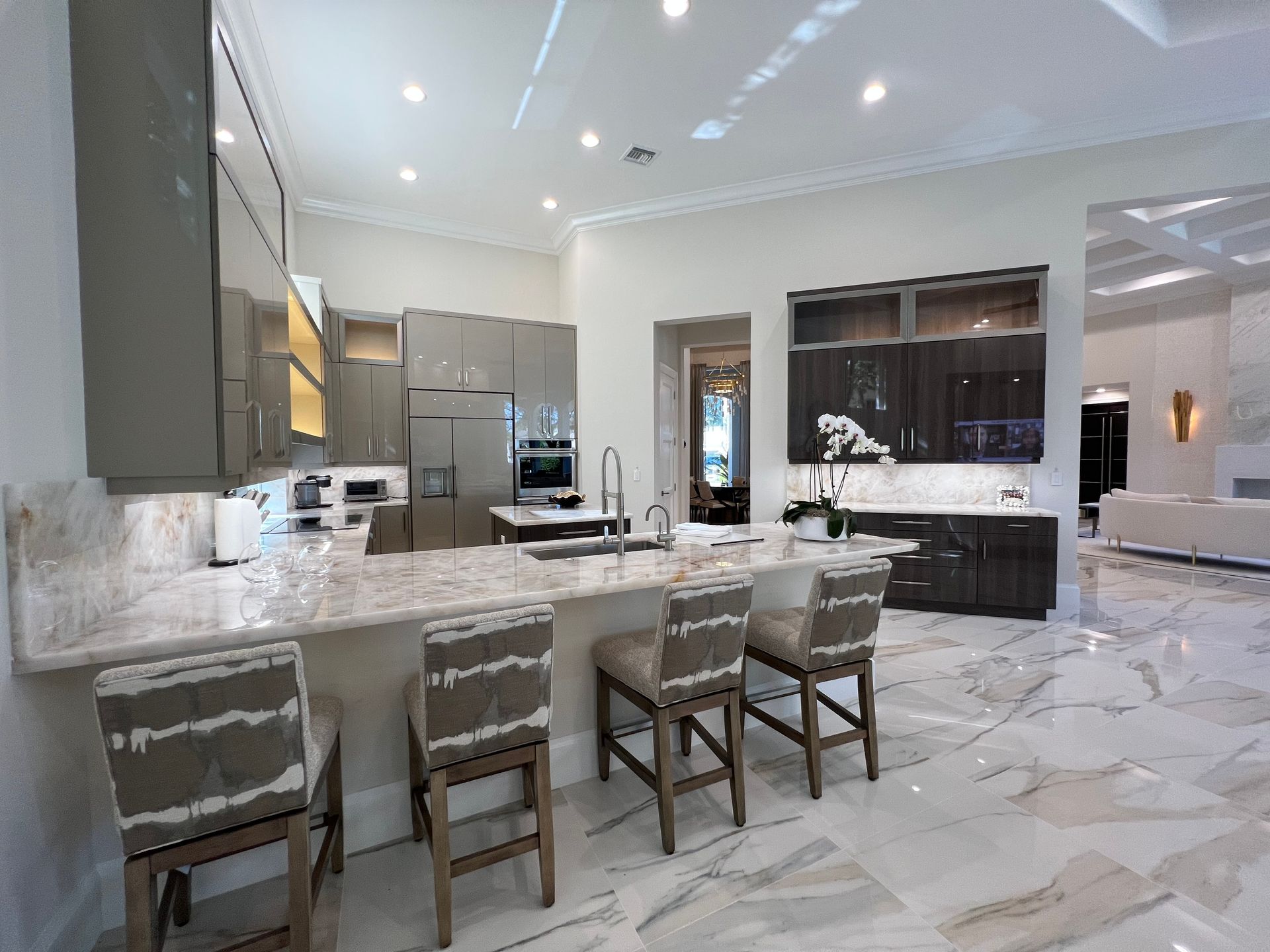 A kitchen with a large island, stools and a refrigerator