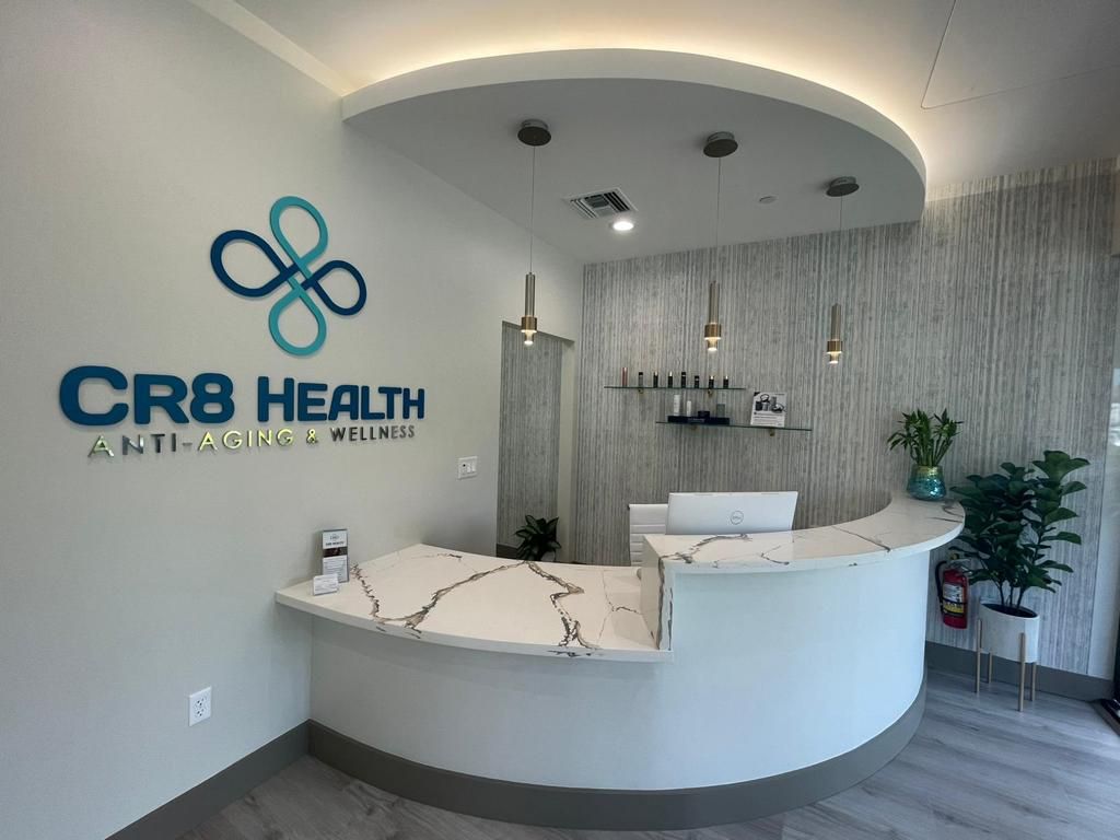 A reception desk in a medical office with a logo on the wall