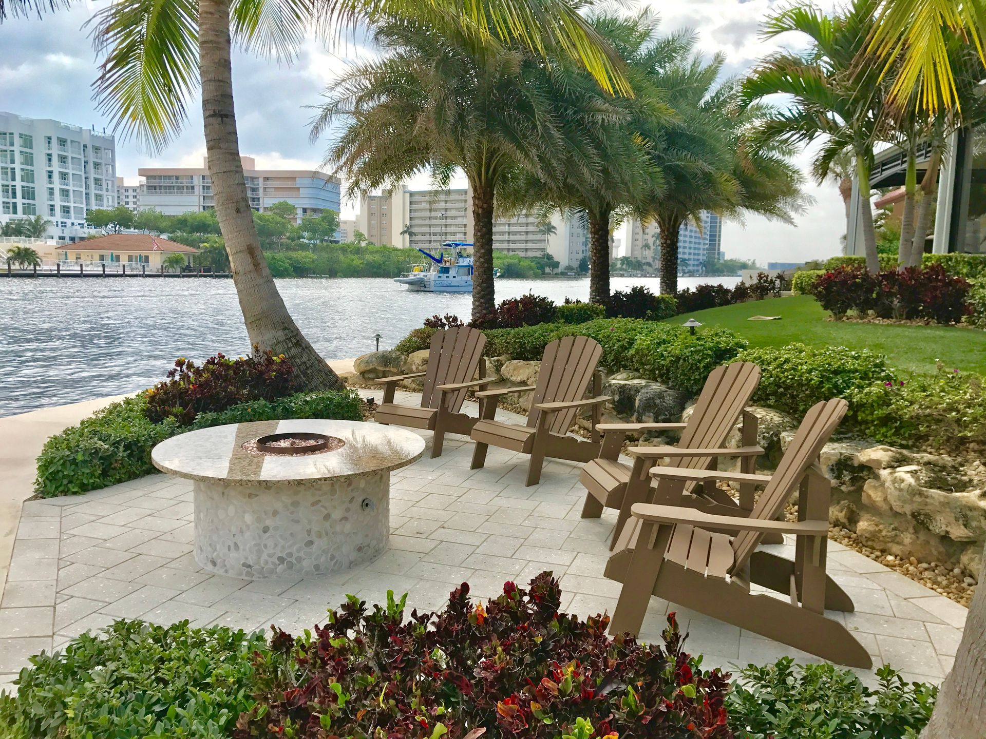 A group of chairs are sitting around a fire pit next to a body of water