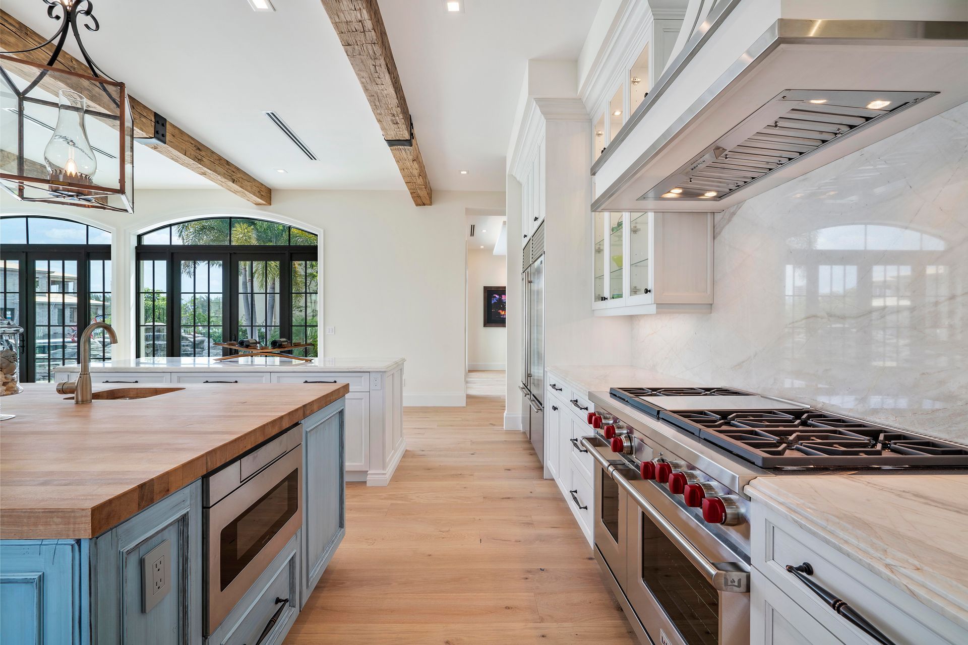 A kitchen with blue cabinets, white cabinets, stainless steel appliances and wooden counter tops