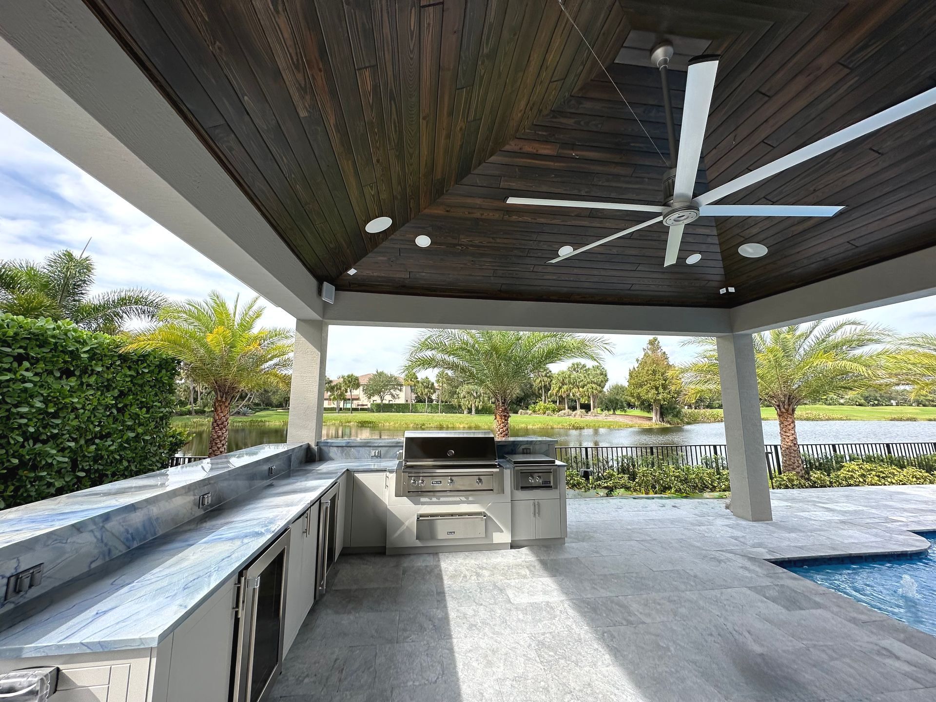 A large outdoor kitchen with a ceiling fan above it
