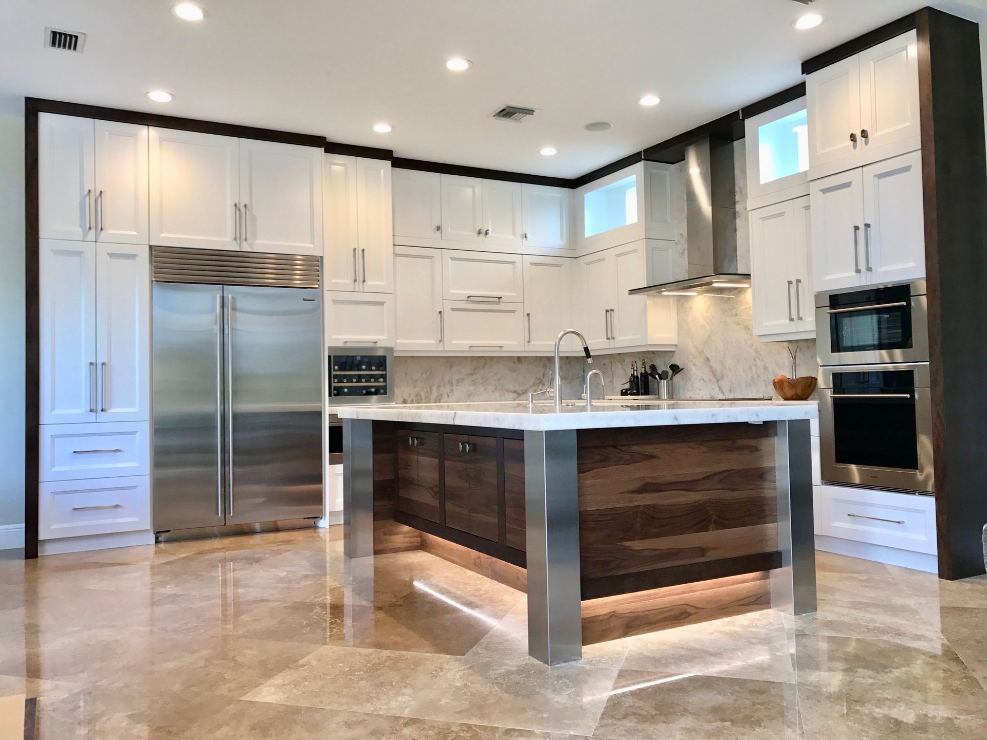 A kitchen with white cabinets, stainless steel appliances, and a large island