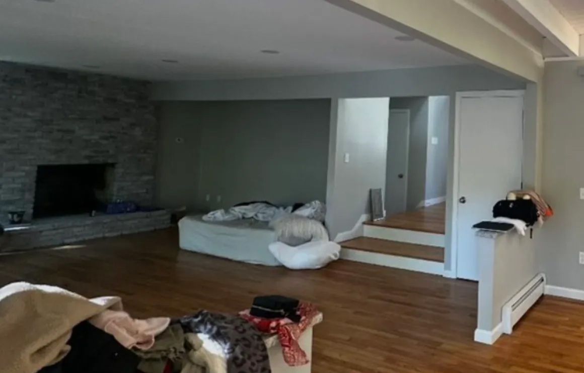 Living room with gray walls, stone fireplace, hardwood floors, and a step up to a doorway.