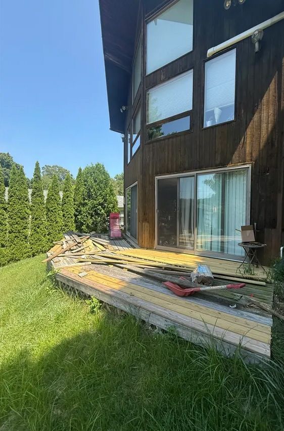 A house with a deck under construction. Yellow and gray deck boards are laid out on a concrete base.