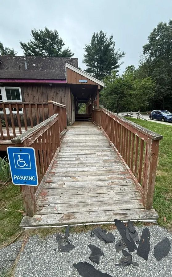 Wooden ramp leading to a building entrance with a handicap parking sign.