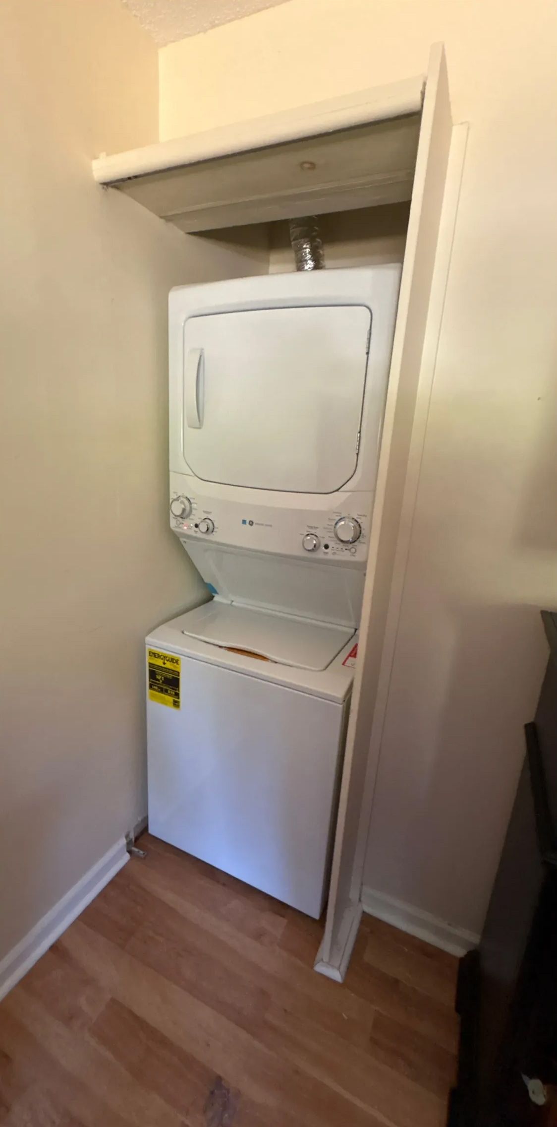 Stacked white washer and dryer unit in a closet.